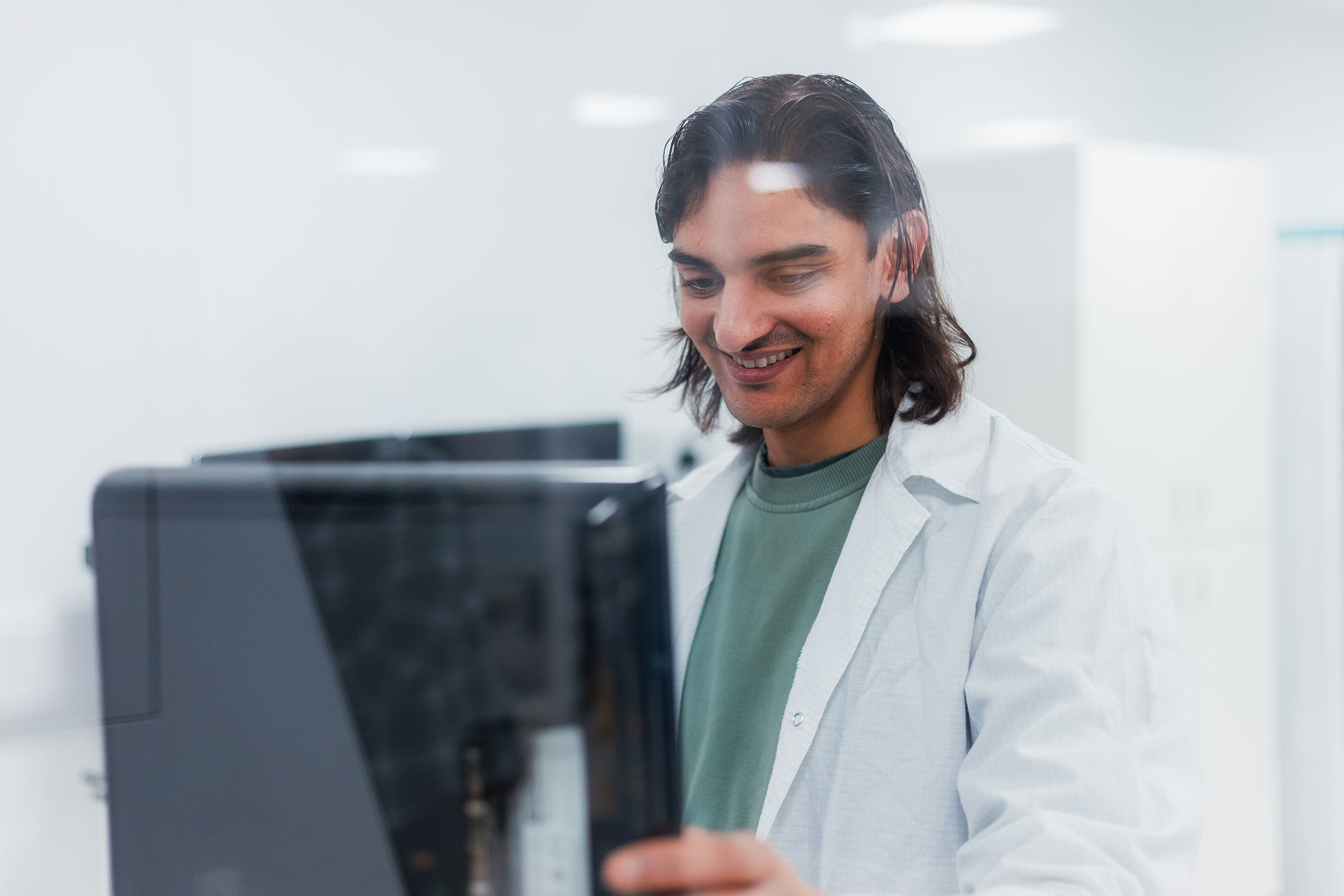 A person in a lab coat interacts with a piece of scientific equipment in a laboratory setting. - CSA Catapult