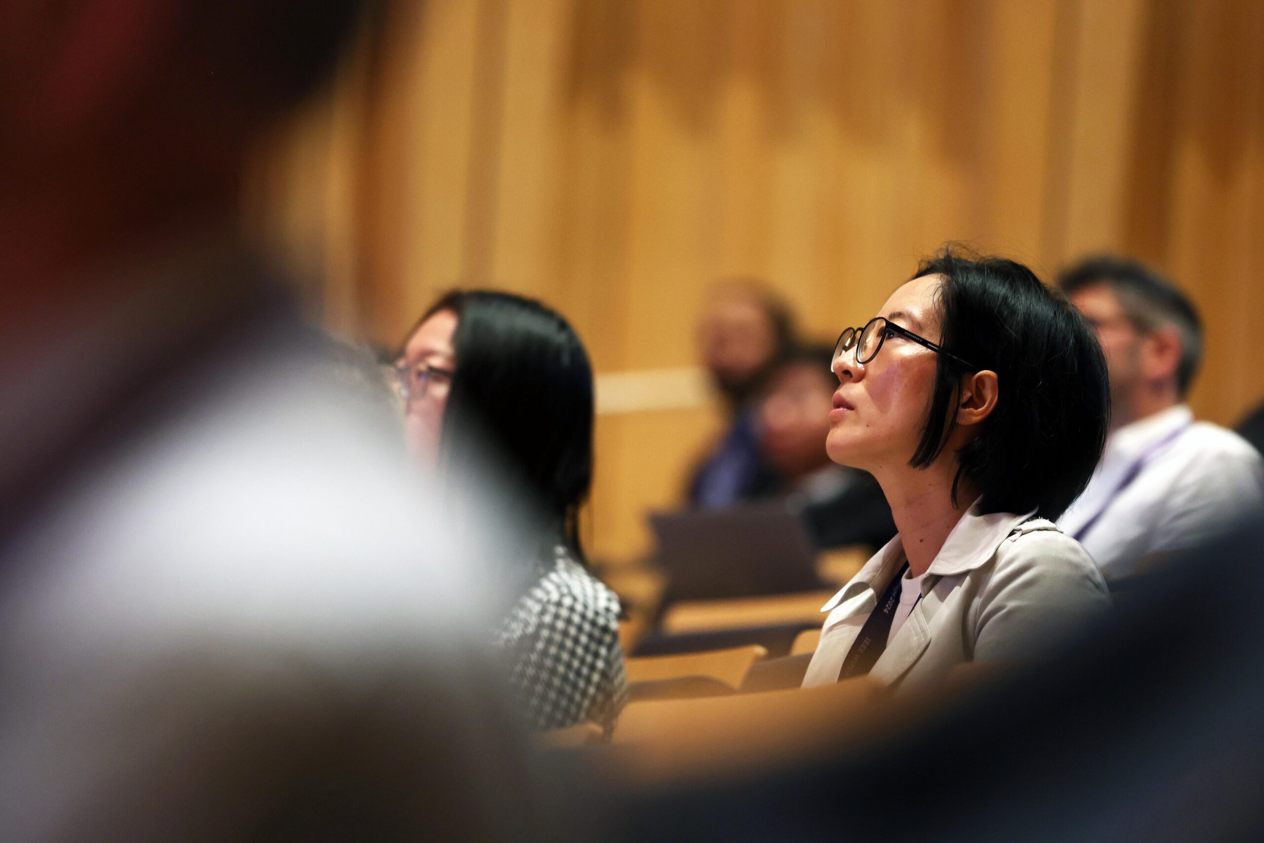 Audience members seated and attentively listening during a presentation in a lecture hall. - CSA Catapult