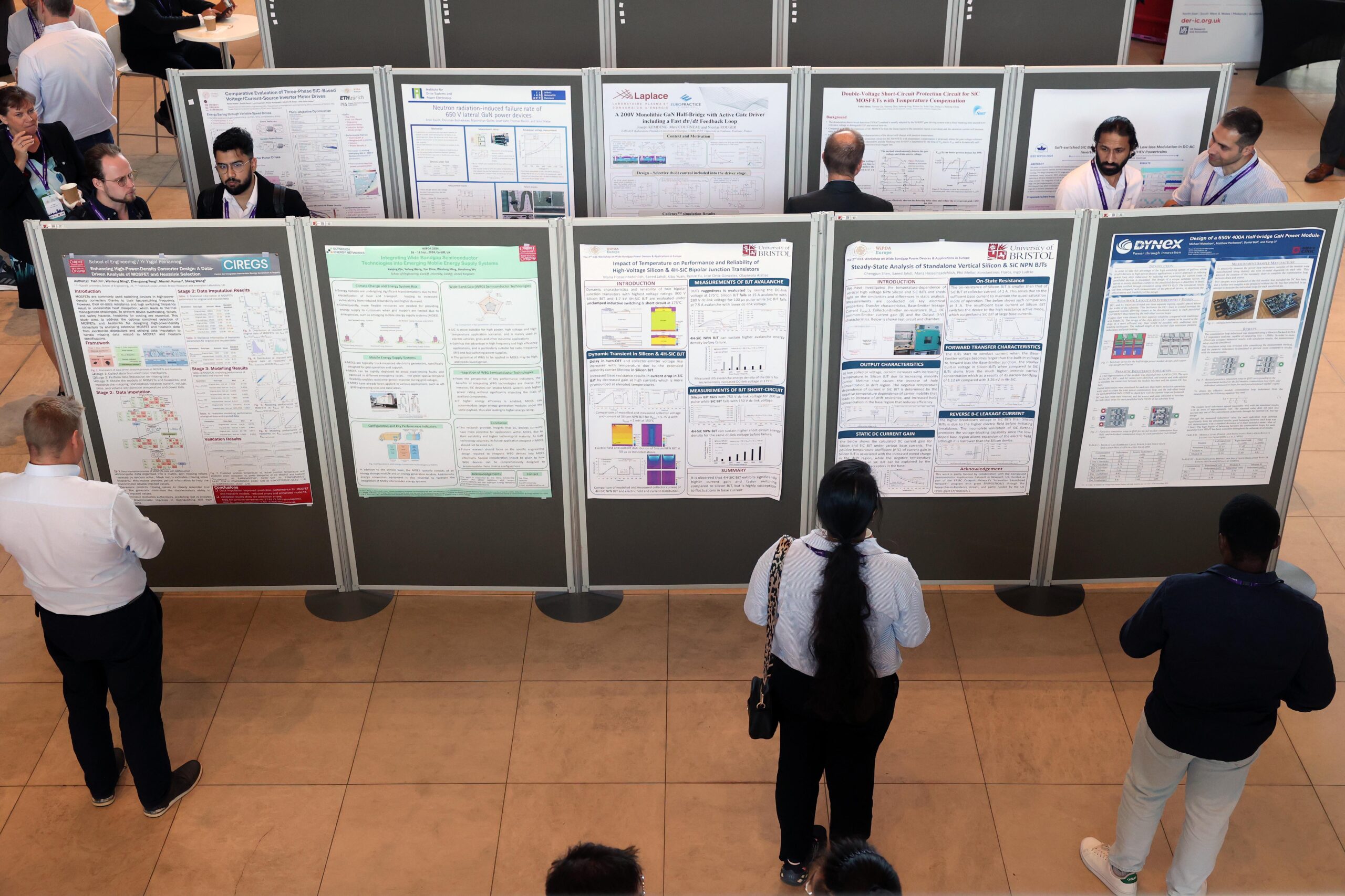 People standing and viewing scientific posters displayed on panels at an exhibition or conference hall. - CSA Catapult