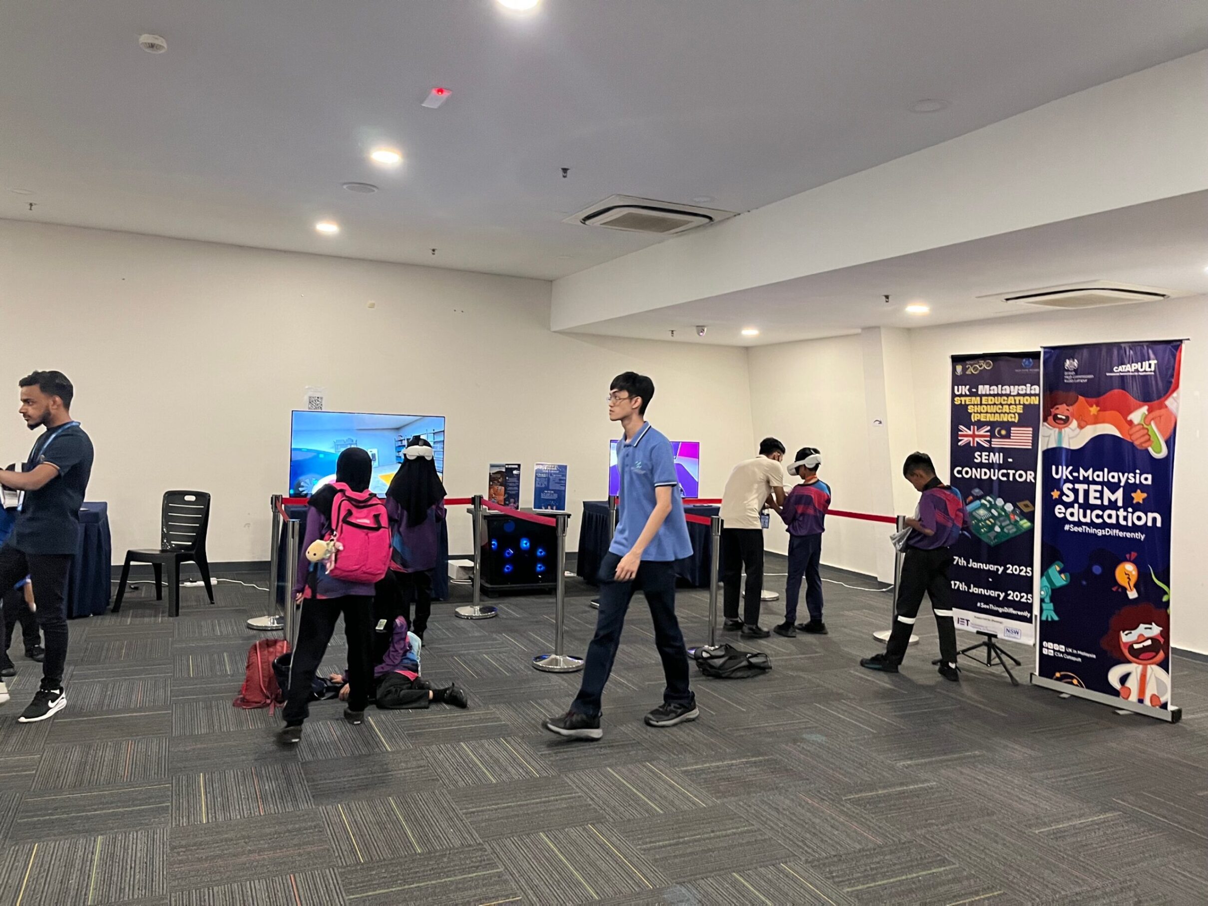 Attendees at an e-STEM event engage with interactive exhibits in a spacious room. - CSA Catapult