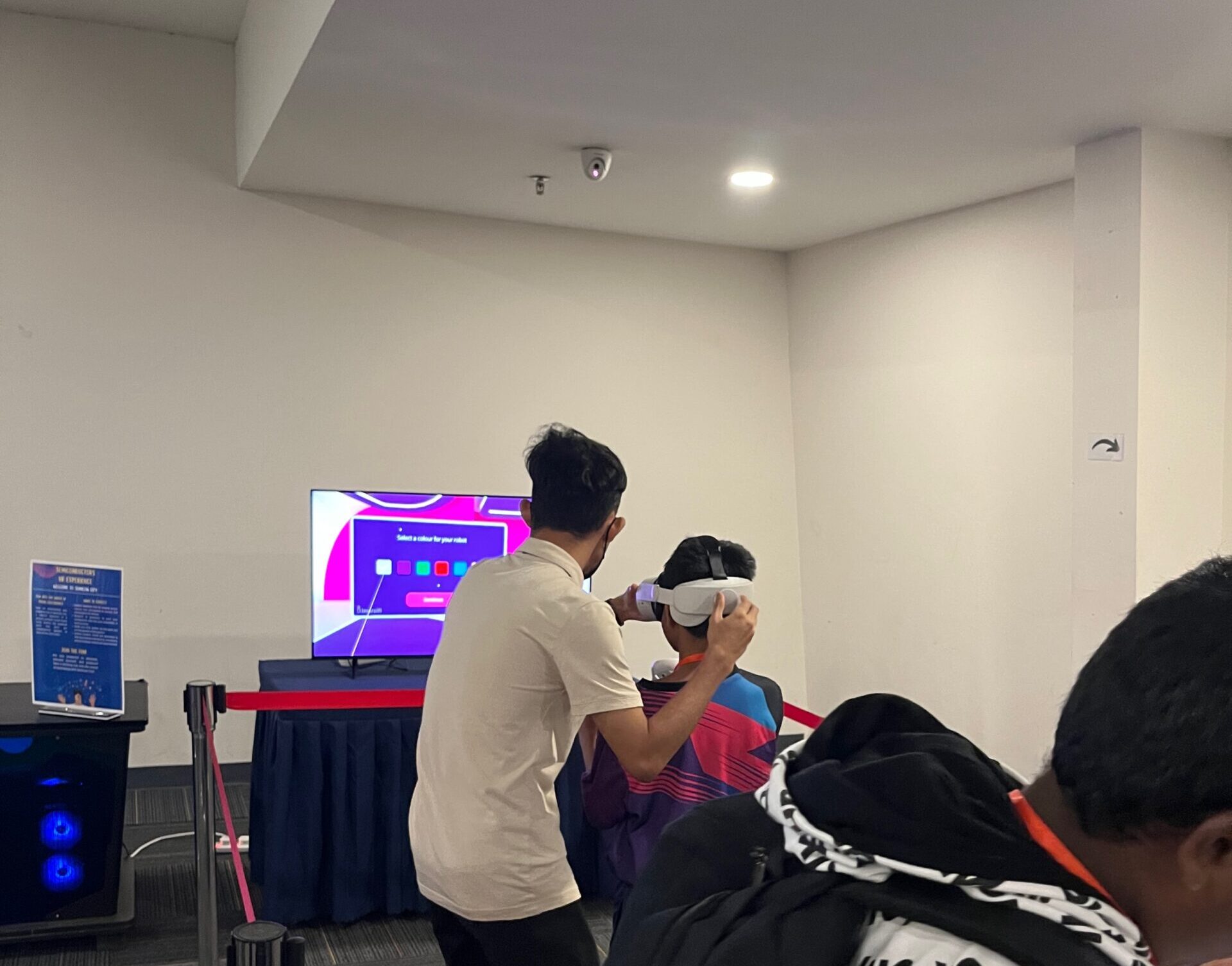 Two people exploring with a virtual reality headset indoors, as a third looks on, intrigued in the foreground. - CSA Catapult