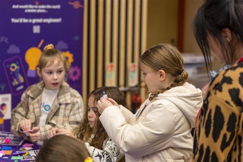 Children engaged in a craft activity at the Cardiff Science Festival 2025, supervised by an adult in a patterned coat. - CSA Catapult