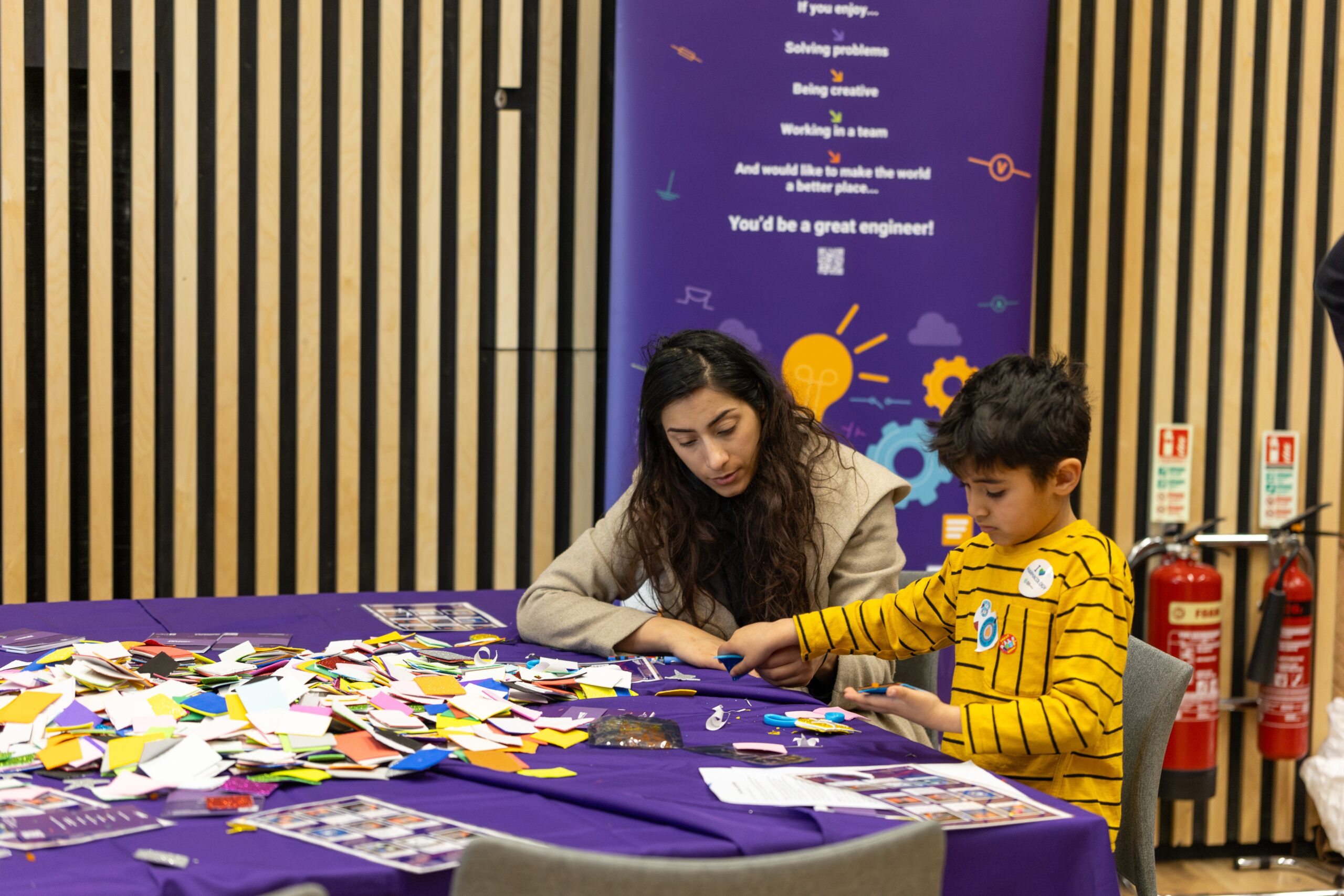 At Cardiff Science Festival 2025, a woman and child craft with colorful paper pieces at their table. - CSA Catapult