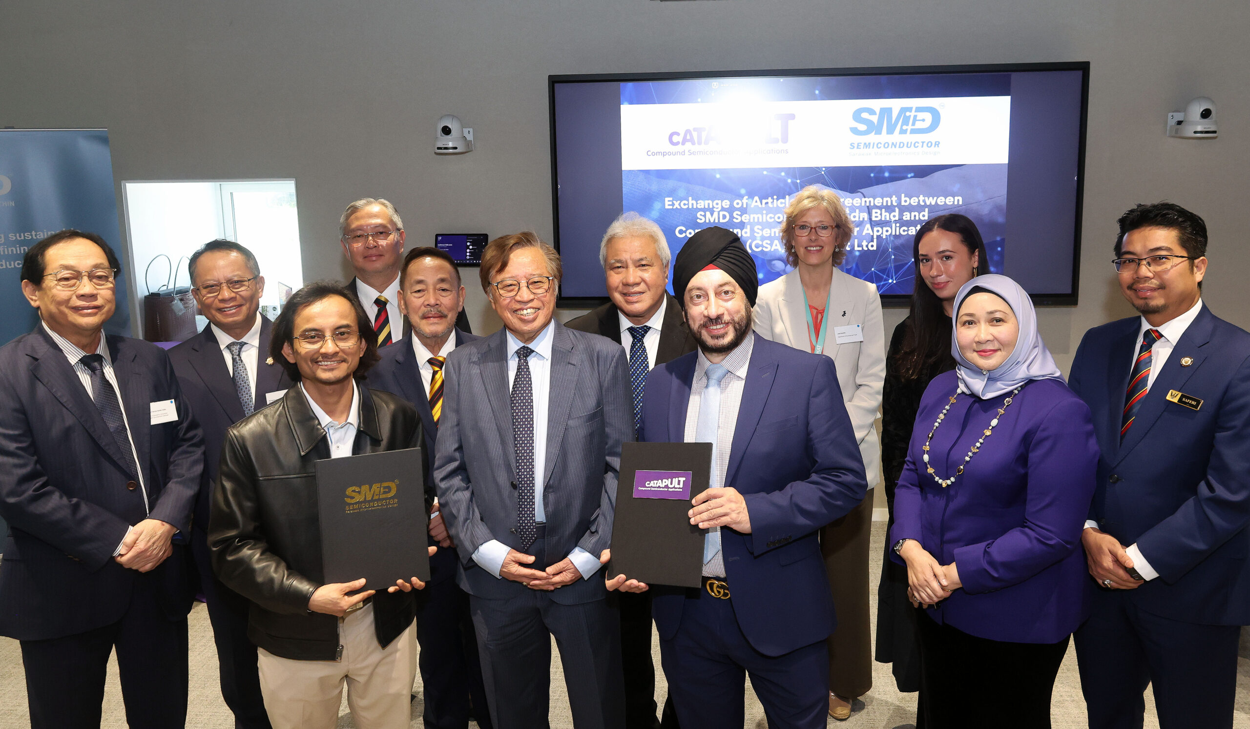 A group in business attire poses with folders at a Sarawak corporate agreement signing event. - CSA Catapult