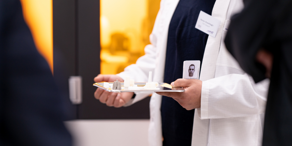 A person in a lab coat carefully examines a tray of GaN components indoors, focusing intently on the tray's contents. - CSA Catapult