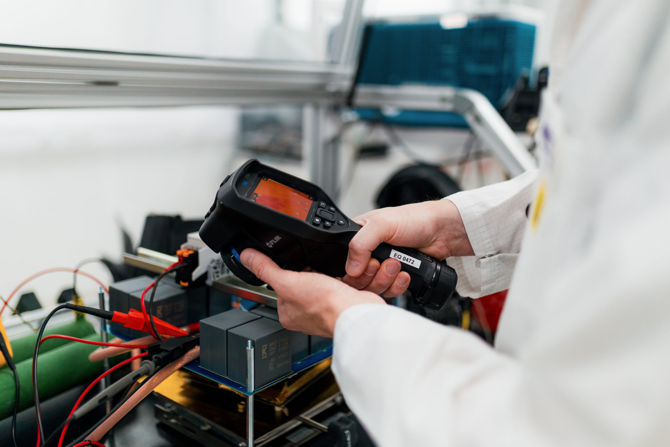 Person in a lab coat uses a handheld thermal imager, highlighting innovation through academic partnership in the lab. - CSA Catapult