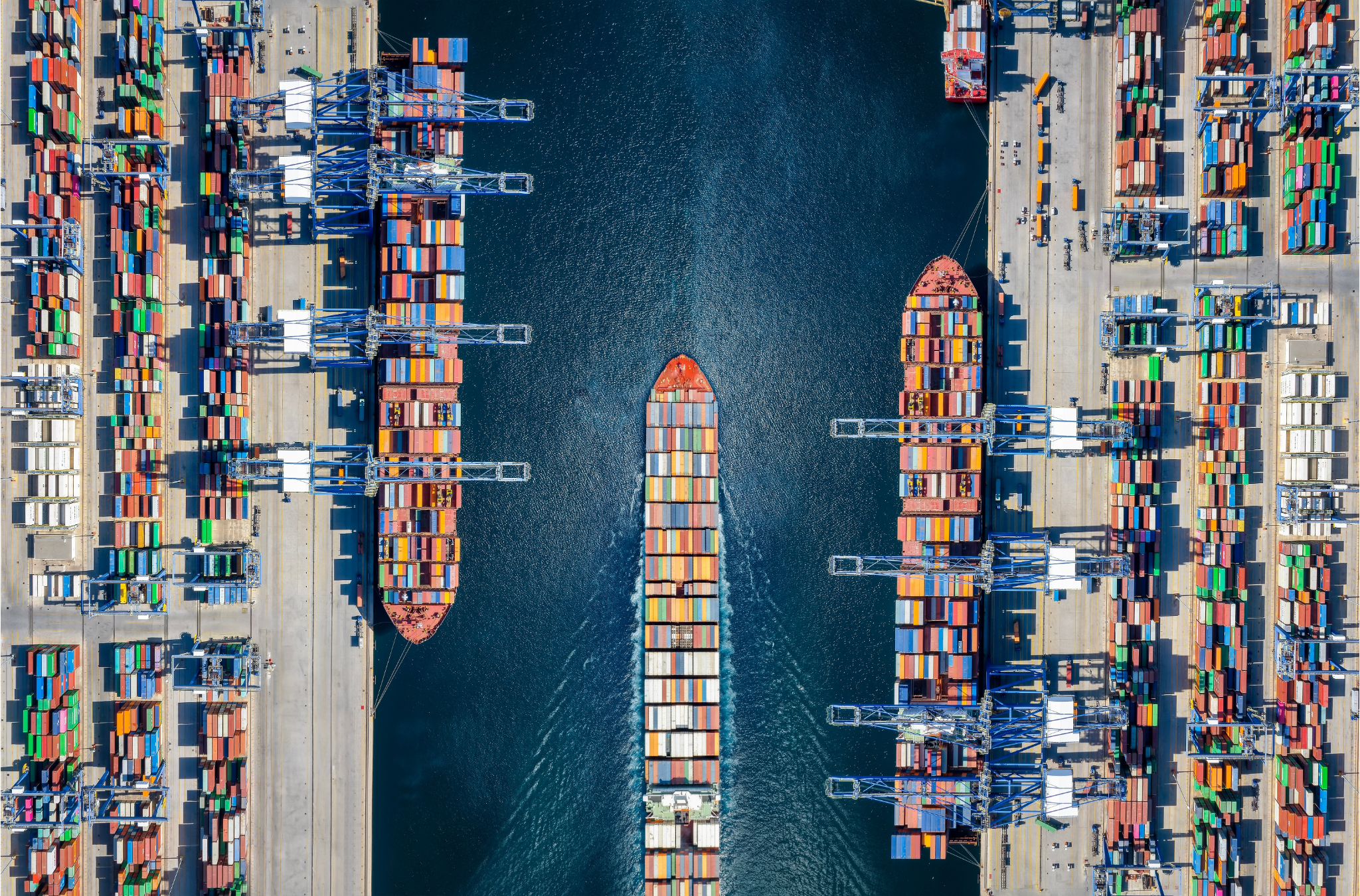 Aerial view of three cargo ships at a busy Wales port, surrounded by stacks of colorful shipping containers. - CSA Catapult