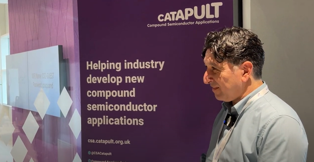 A man stands next to a purple Catapult banner in Sarawak about compound semiconductor applications. - CSA Catapult