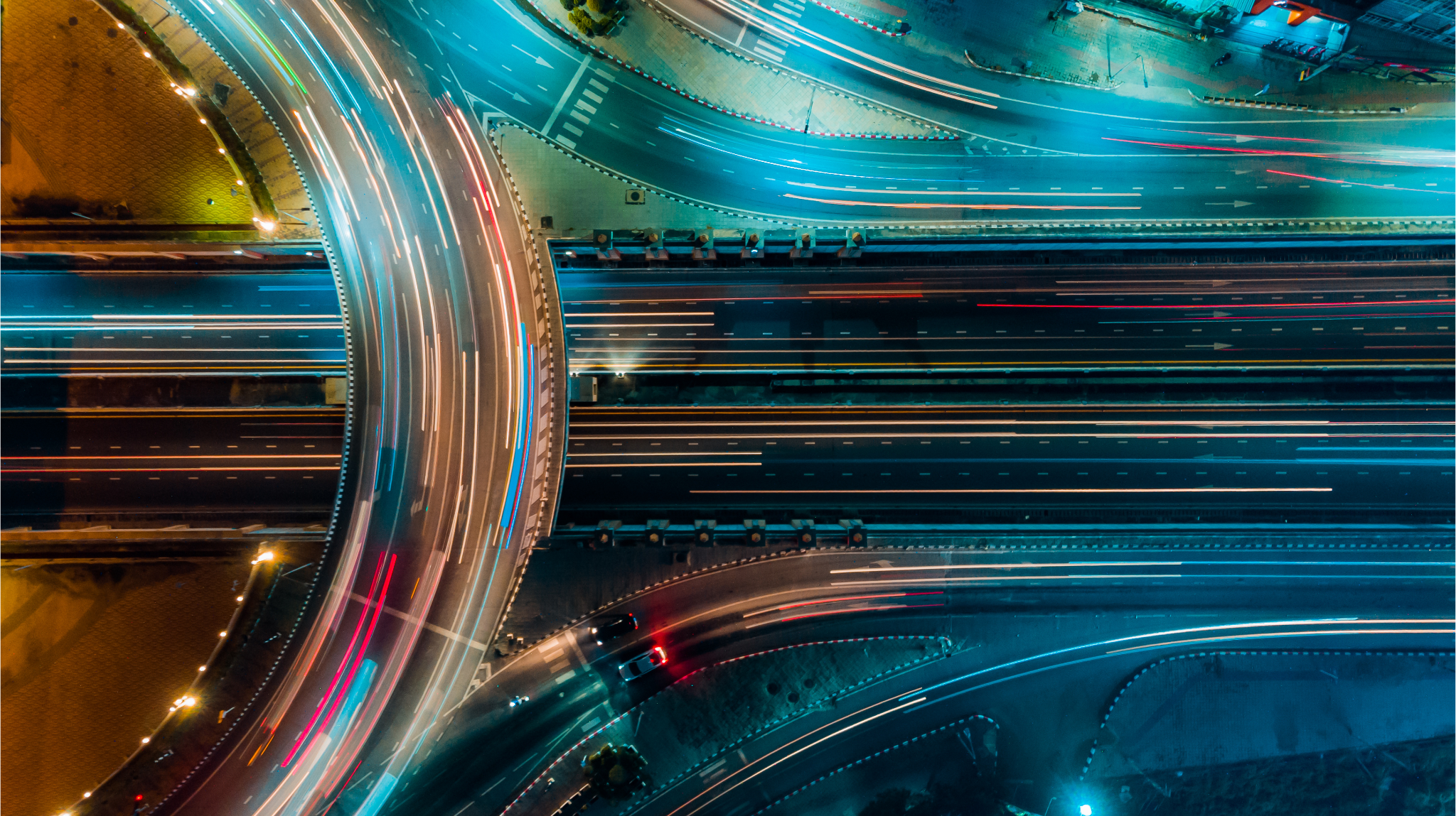 Aerial view of a busy highway interchange at night with streaks of car lights and glowing streetlights. - CSA Catapult
