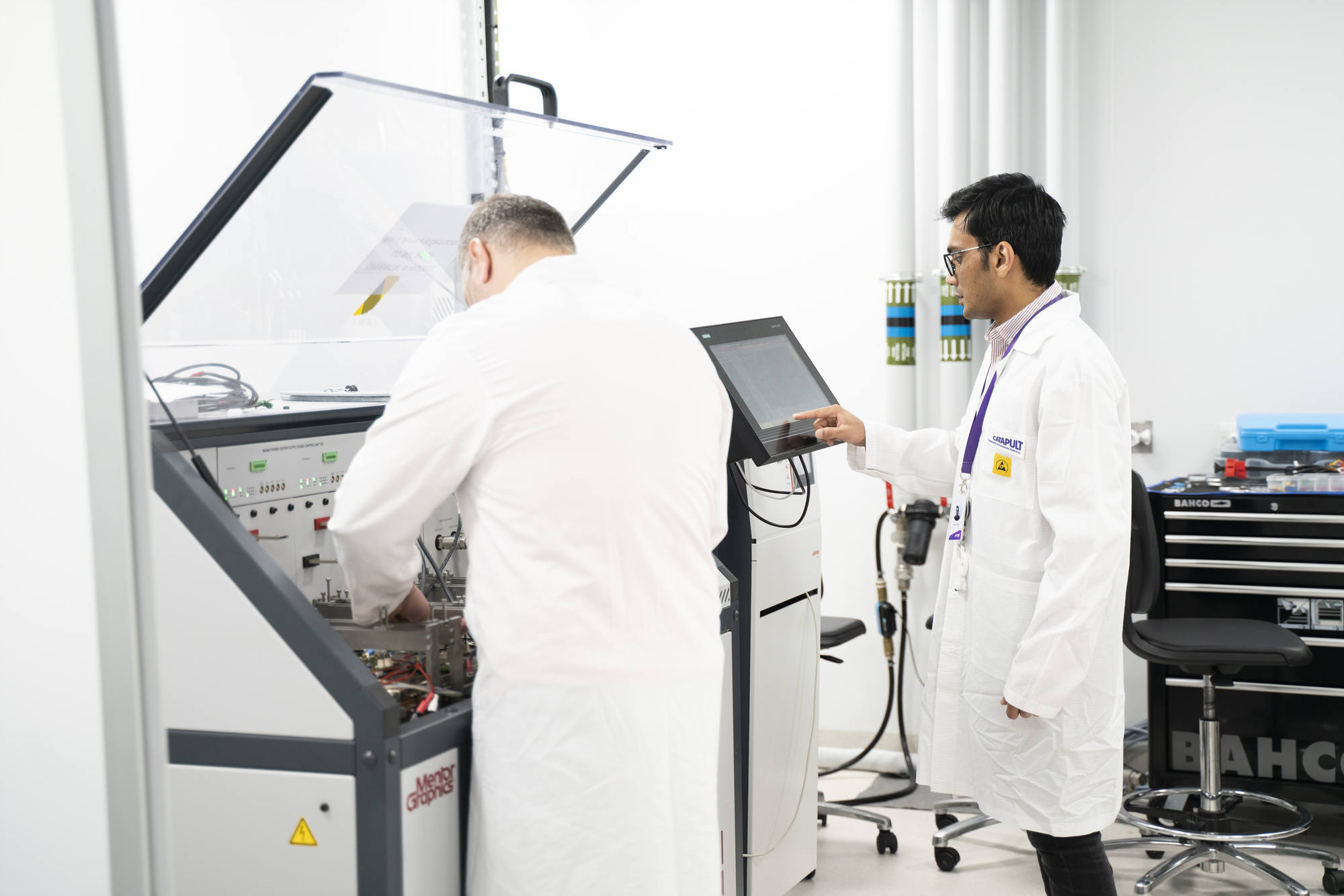 Two scientists in lab coats work with scientific equipment and a touchscreen in a laboratory setting. - CSA Catapult