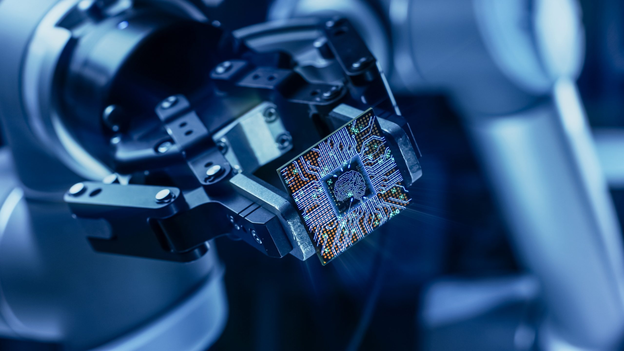 A robotic arm holds a microchip in a high-tech, blue-lit laboratory setting. - CSA Catapult