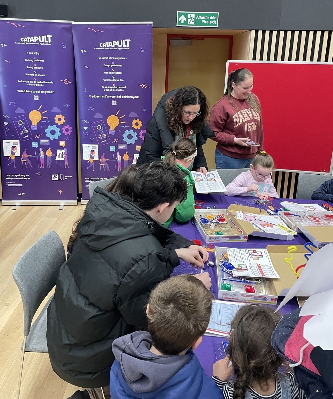 Adults and children work together on STEM activities at a table during an educational e-event. - CSA Catapult