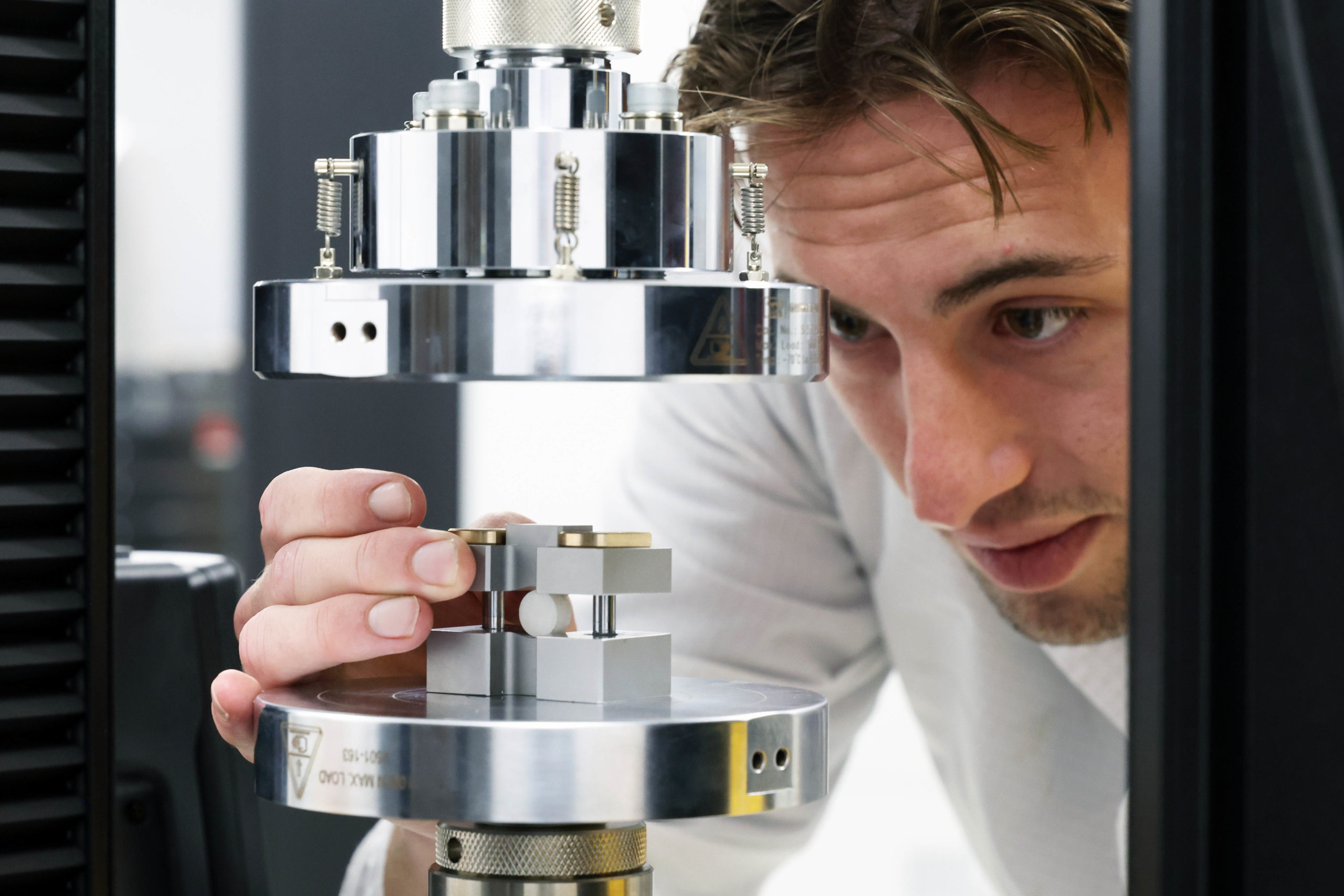A man closely examines and adjusts a piece of equipment in a laboratory setting. - CSA Catapult